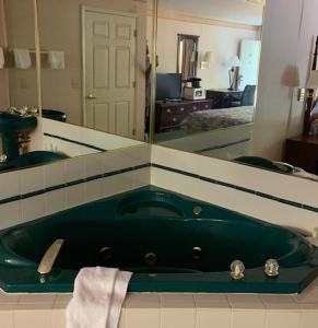 a bathroom with a green tub in front of a mirror at Executive Inn Yanceyville in Yanceyville