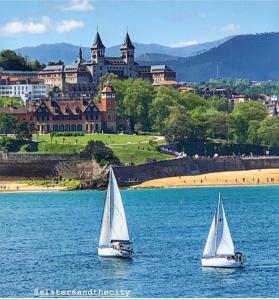 two sailboats in the water in front of a castle at OLA Apartamento - Perla Boutique Apartamentos in Donostia-San Sebastián