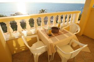 een tafel en stoelen op een balkon met uitzicht op de oceaan bij Apts Mladen - family friendly in Vrsi