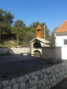 a building with a brick oven next to a stone wall at Apartments Ivo - sea view terrace in Veli Rat