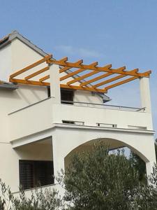 a white house with wooden beams on top of it at Apartments Ivo - sea view terrace in Veli Rat