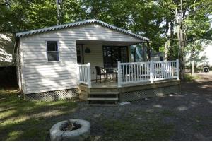 Cabaña blanca pequeña con porche y mesa en Camping Chalets Lac St-Augustin, en Quebec