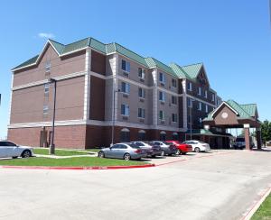 un gran edificio con coches estacionados en un estacionamiento en Country Inn & Suites by Radisson, DFW Airport South, TX, en Irving