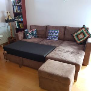 sofá con almohadas y reposapiés en la sala de estar en Peaceful farm apartment, en Eiðar