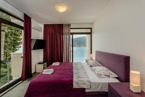 a bedroom with a large bed with a large window at Apartments Joy in Herceg-Novi