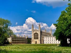 un grand bâtiment dans un champ avec un ciel bleu dans l'établissement The Birches, à Cambridge