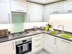 La cuisine est équipée de placards blancs et d'un four avec plaques de cuisson. dans l'établissement The Birches, à Cambridge
