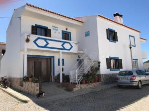 een wit huis met een auto ervoor geparkeerd bij Casa Da Estela in Carrapateira