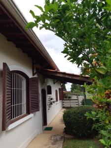 una vista exterior de una casa con ventanas de madera y un árbol en Hospedagem UniCanto, en Campinas