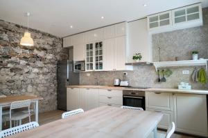 cocina con mesa de madera y pared de piedra en Premium Hostel Kobarid, en Kobarid