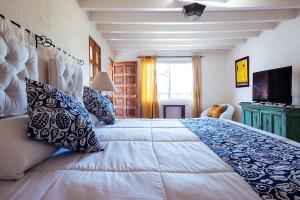 a bedroom with a large bed with blue and white pillows at Pied à Terre at Casitas Aparicio in San Miguel de Allende