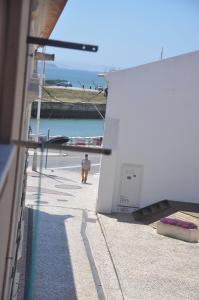 un hombre caminando por una acera junto al océano en Tic Tac Apartment en Peniche