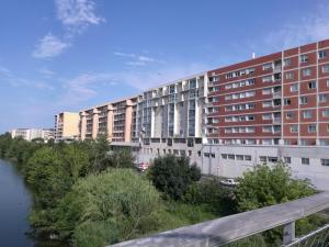 a large building next to a river and a bridge at T2 Centre Ville Place Méditerranée in Perpignan