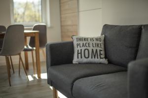a gray couch with a pillow that says there is no place like home at Pokoje Na Szlaku in Lądek-Zdrój