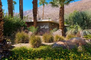 una señal en medio de un jardín con palmeras en Desert Hills en Palm Springs