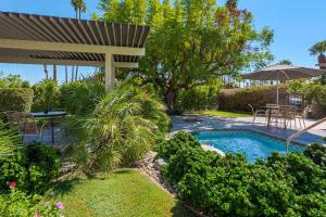 un patio trasero con piscina, mesa y sombrilla en Desert Hills en Palm Springs
