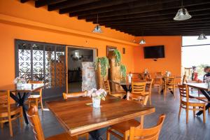 un restaurante con paredes de color naranja, mesas y sillas en El Macehual, en San Miguel de Allende