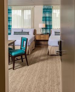 a bedroom with two beds and a blue chair at Bridgewater Hotel, Trademark Collection by Wyndham in Fairbanks