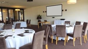 a conference room with tables and chairs and a screen at Barwon Heads Resort in Barwon Heads