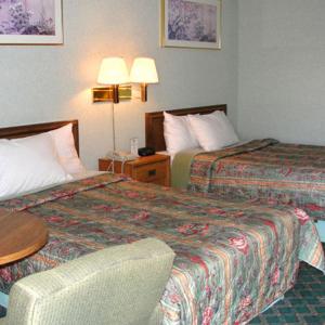 Habitación de hotel con 2 camas, mesa y silla en Royal Inn en Alcoa