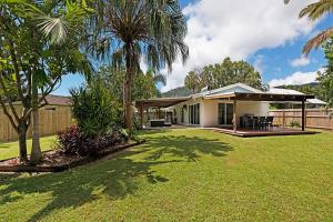 a house with a yard with palm trees at Whitsunday Palms by HamoRent in Airlie Beach