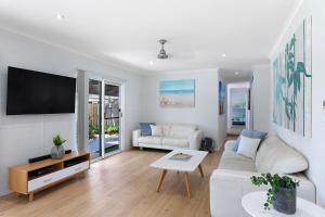 sala de estar con sofá blanco y TV en Whitsunday Palms by HamoRent, en Airlie Beach