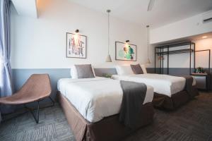 a hotel room with two beds and a chair at Z HOTEL in Johor Bahru