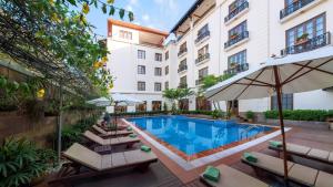 uma piscina do hotel com espreguiçadeiras e um guarda-sol em Steung Siemreap Hotel em Siem Reap