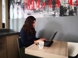 a woman sitting at a table with a laptop at Metropolis Suites Ejecutivas in Puebla