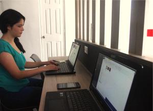 a woman sitting at a table with two laptop computers at Metropolis Suites Ejecutivas in Puebla