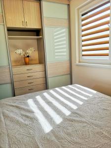 a bedroom with a bed and a dresser and a window at Apartamentai Karklėje in Karklė