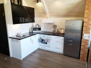 a kitchen with white cabinets and a stainless steel refrigerator at Apartamentai Karklėje in Karklė