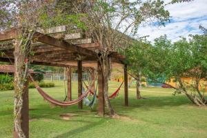 a hammock in a park with two trees at Bomtempo Itaipava by Castelo Itaipava in Itaipava