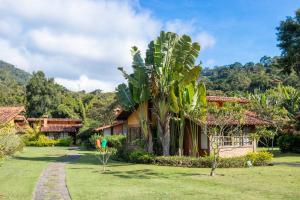 une maison avec un palmier dans la cour dans l'établissement Bomtempo Itaipava by Castelo Itaipava, à Itaipava