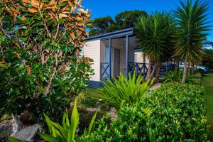 a small white cottage with trees and bushes at Clarence Head Caravan Park in Iluka