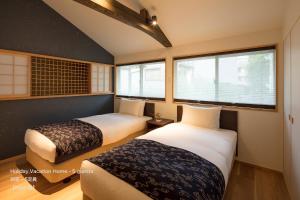 two beds in a room with two windows at THE MACHIYA VILLA Sanjo Shirakawa Koji in Kyoto