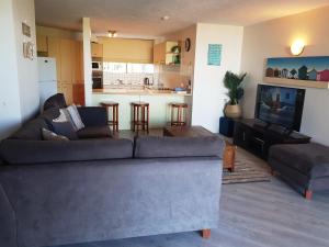 Una sala de estar con un sofá y un televisor. en Casablanca Beachfront Apartments, en Caloundra