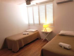2 camas en una habitación con ventana y lámpara en Casablanca Beachfront Apartments, en Caloundra 13 fotos más