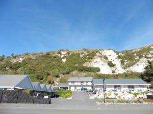 a white building with a mountain in the background at Admiral Court Motel Kaikoura in Kaikoura