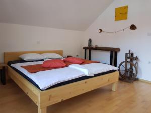 Schlafzimmer mit einem Holzbett mit roten und weißen Kissen in der Unterkunft Guesthouse S in Luče
