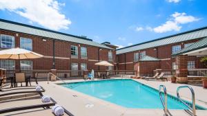 einem Pool vor einem Backsteingebäude in der Unterkunft Best Western Plus Addison/Dallas Hotel in Addison