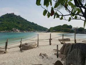 a sandy beach with a fence and the ocean at Nangyuan Island Dive Resort in Ko Tao