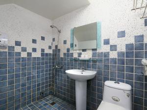 a blue tiled bathroom with a sink and a toilet at Leisure Homestay in Hualien City