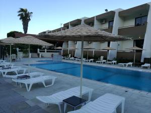 a pool with chairs and umbrellas next to a hotel at Golden days in Afantou