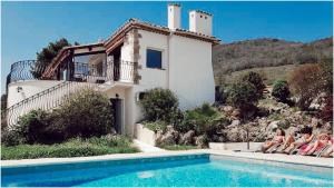 a group of people sitting next to a house with a swimming pool at Villa Ruzanna in Mandelieu-La Napoule