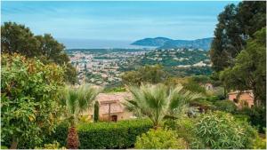 a view of a city from a garden with palm trees at Villa Ruzanna in Mandelieu-La Napoule