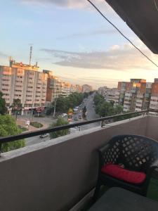 une chaise sur un balcon avec vue sur la ville dans l'établissement Hellen's Ultracentral Apartament, à Buzău