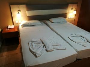 two beds in a hotel room with towels on them at Golden days in Afantou