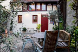 patio con mesa, sillas y puerta roja en Wenkheimer Hof Ferienwohnung, en Iphofen