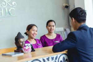 um homem sentado numa mesa com duas mulheres e uma estátua em Home Chic Hotel em Phnom Penh